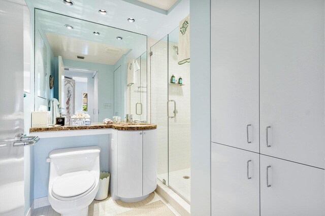 bathroom featuring tile patterned floors, an enclosed shower, vanity, and toilet