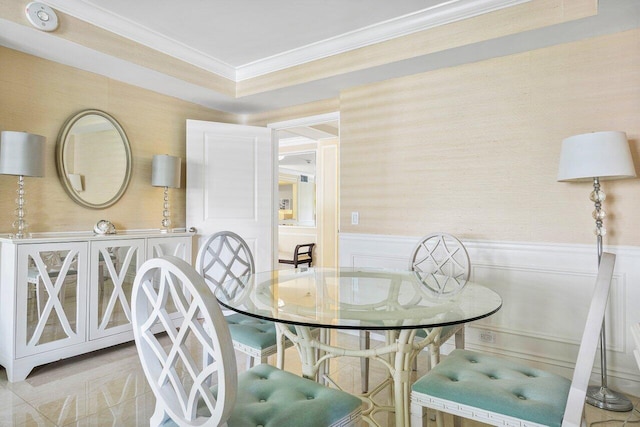 dining room with a decorative wall, wainscoting, and crown molding