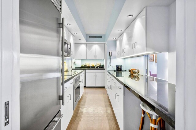 kitchen with appliances with stainless steel finishes, white cabinets, light tile patterned floors, and sink