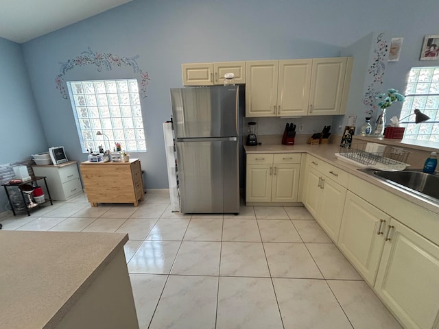 kitchen featuring light tile patterned floors, sink, a healthy amount of sunlight, and stainless steel refrigerator