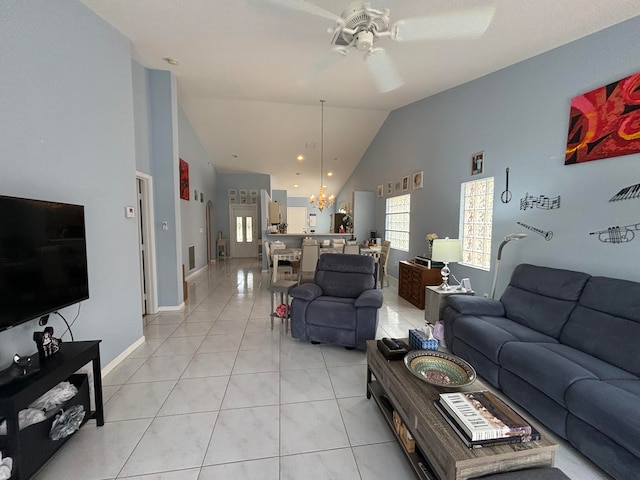 tiled living room featuring high vaulted ceiling and ceiling fan with notable chandelier