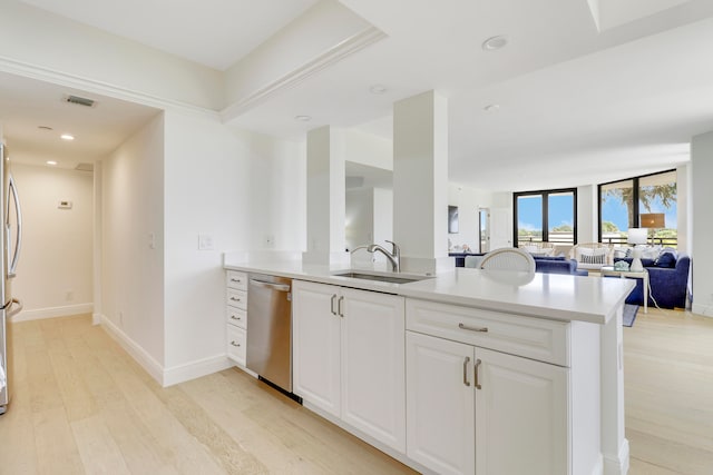 kitchen featuring stainless steel appliances, kitchen peninsula, sink, white cabinets, and light hardwood / wood-style floors