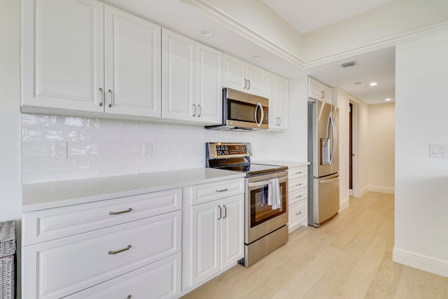 kitchen featuring backsplash, appliances with stainless steel finishes, white cabinetry, and light hardwood / wood-style floors