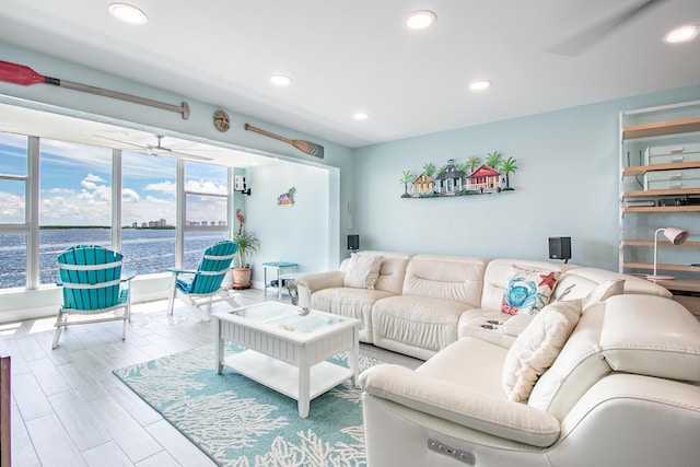 living area with a water view, a ceiling fan, wood finished floors, and recessed lighting