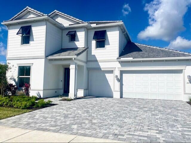 view of front of property featuring decorative driveway, an attached garage, and stucco siding