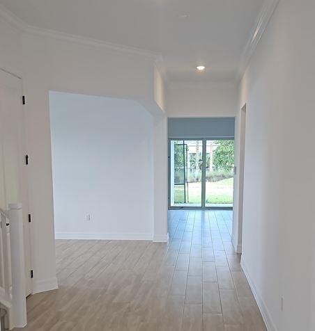 spare room featuring baseboards, light wood finished floors, and crown molding