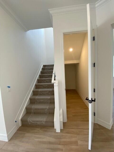 staircase featuring baseboards, ornamental molding, and wood finished floors