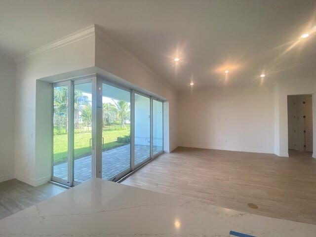 kitchen featuring white cabinets, stainless steel fridge, ornamental molding, and wood-type flooring