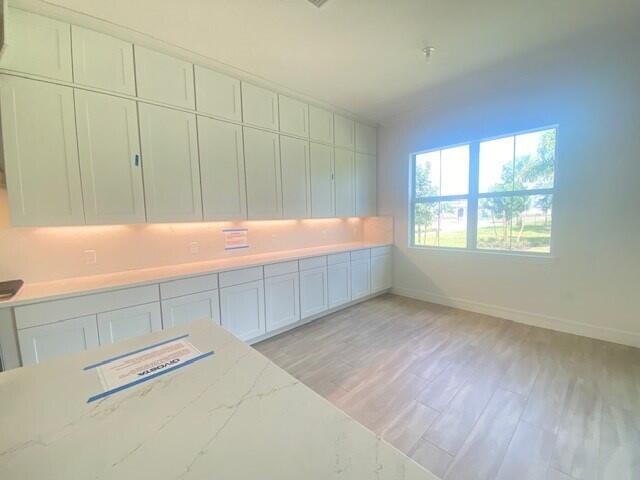 kitchen with white cabinets, light hardwood / wood-style floors, and light stone counters