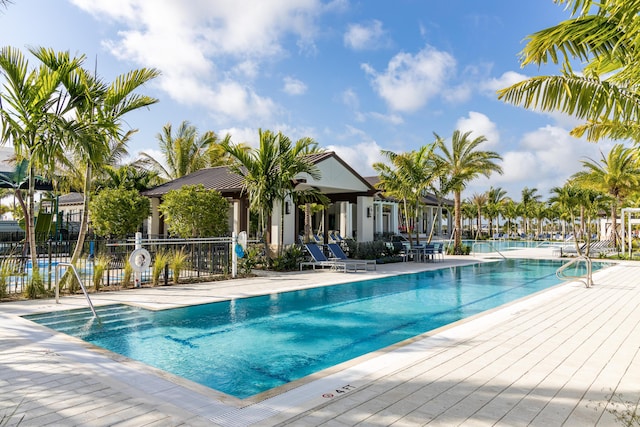 community pool with a patio and fence