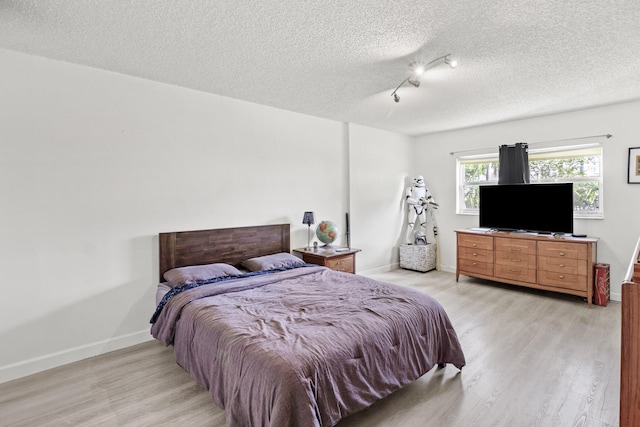 bedroom with a textured ceiling and light hardwood / wood-style floors