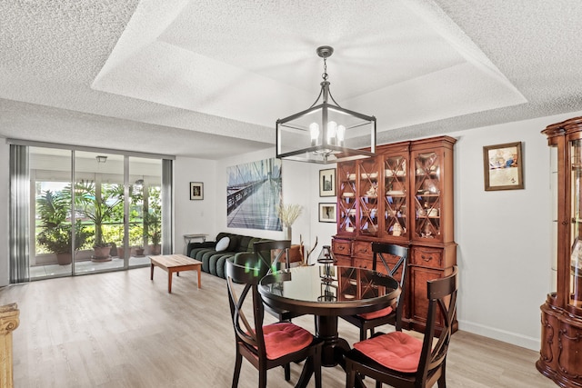 dining room with light wood-type flooring, a textured ceiling, and a notable chandelier