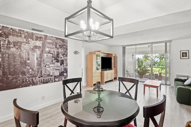 dining area featuring a textured ceiling, light hardwood / wood-style flooring, and an inviting chandelier