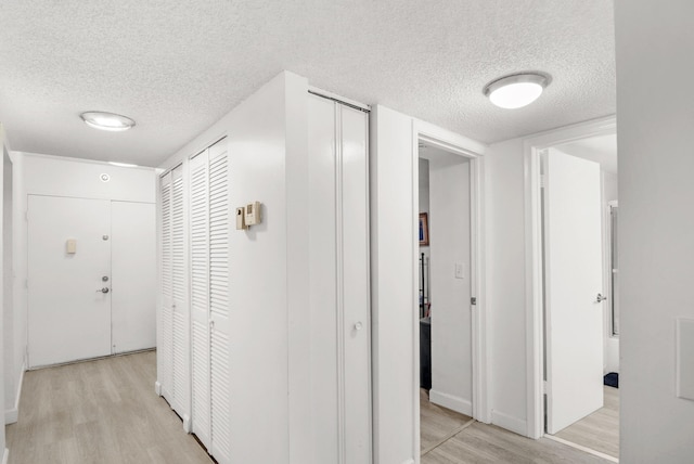 hall featuring light wood-type flooring and a textured ceiling