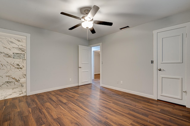 empty room with ceiling fan, dark wood-type flooring, and tile walls