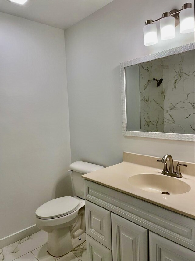 bathroom with a tile shower, vanity, and toilet