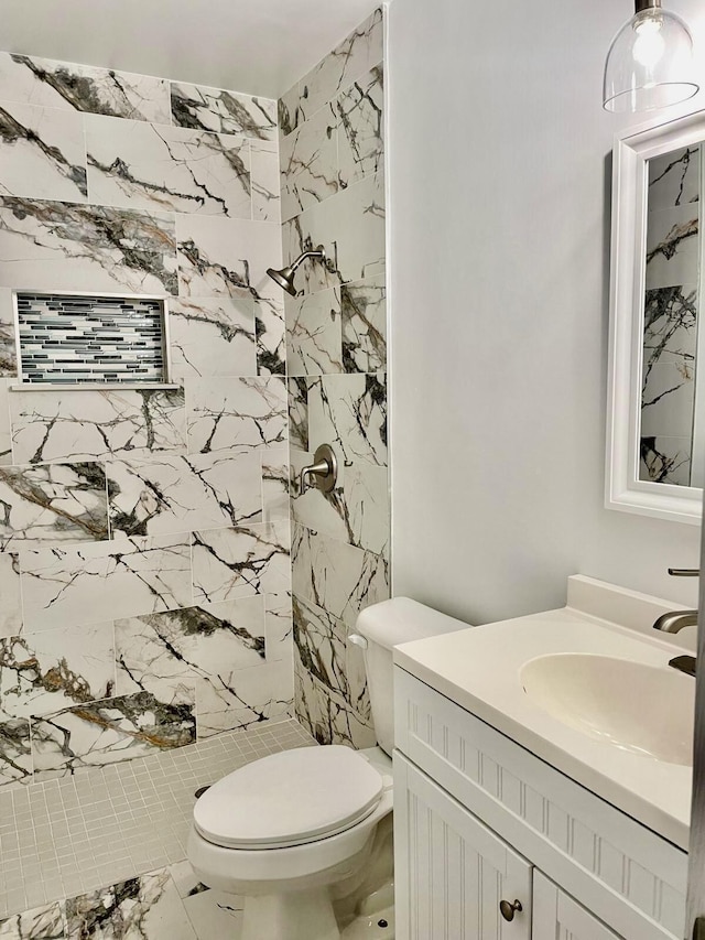 bathroom featuring vanity, tiled shower, and toilet