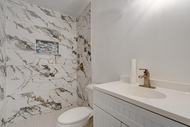 bathroom with vanity, toilet, and tiled shower