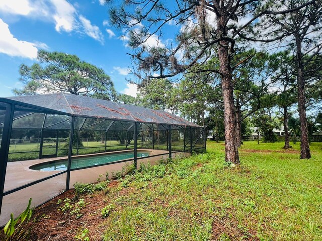 view of yard with glass enclosure, a storage unit, and a pool