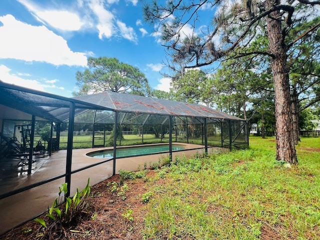 view of pool featuring a yard, a patio area, and glass enclosure