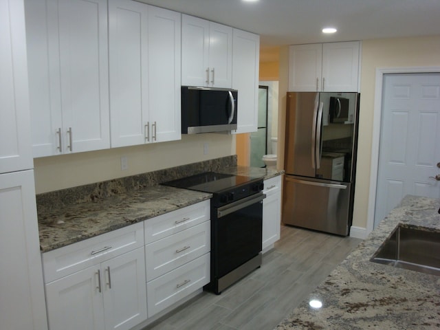 kitchen with white cabinetry, light hardwood / wood-style floors, stainless steel appliances, and stone counters