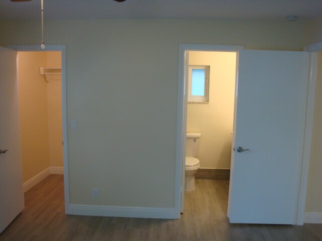 bedroom with a walk in closet, a closet, hardwood / wood-style flooring, and ensuite bathroom