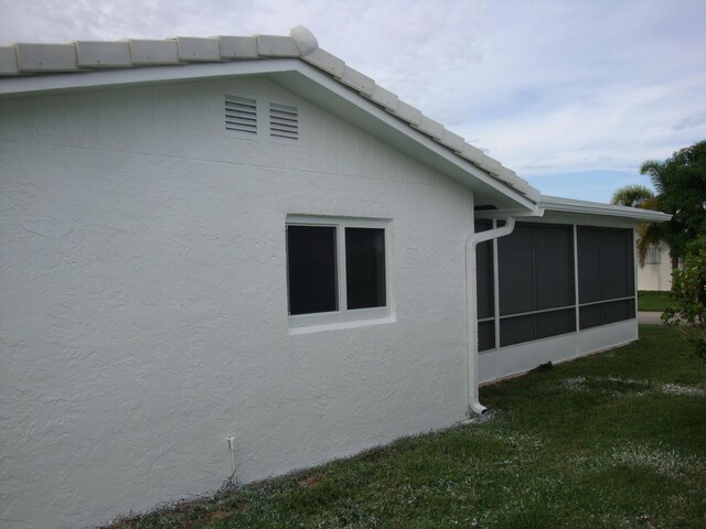 view of side of home featuring a lawn and a sunroom