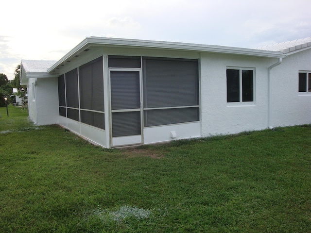 view of home's exterior with a sunroom and a lawn