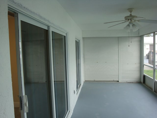 unfurnished sunroom with ceiling fan