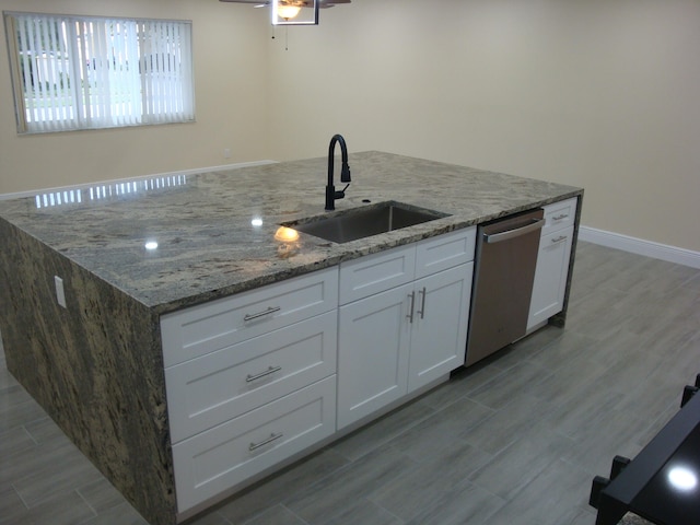 kitchen featuring sink, stainless steel dishwasher, white cabinetry, and stone countertops