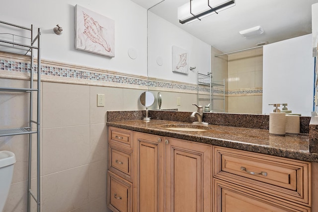 bathroom featuring tile walls, vanity, toilet, and walk in shower