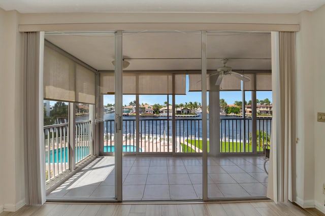 unfurnished sunroom featuring ceiling fan and a water view