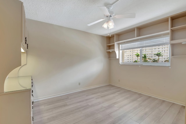 spare room with a textured ceiling, ceiling fan, and light hardwood / wood-style flooring