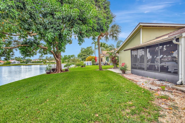 view of yard with a sunroom and a water view