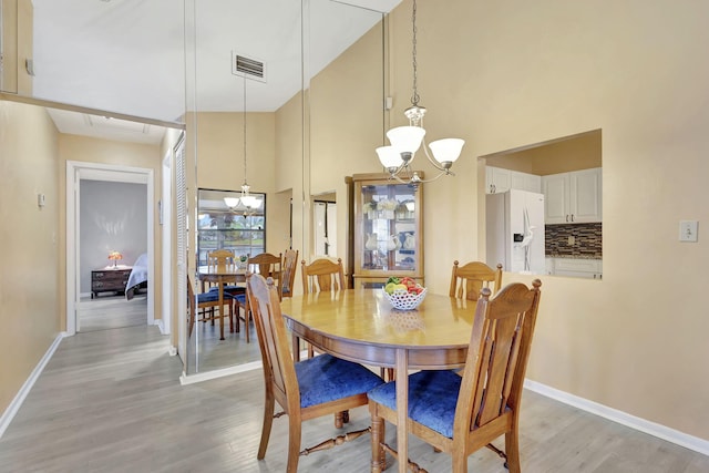 dining space featuring high vaulted ceiling, light hardwood / wood-style floors, and an inviting chandelier