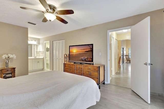 bedroom featuring light wood-type flooring, ceiling fan, and ensuite bath