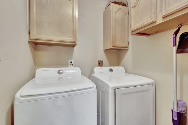 laundry room featuring washer and clothes dryer and cabinets