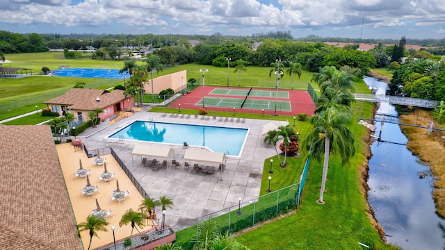 view of pool with a lawn, a water view, and a patio area