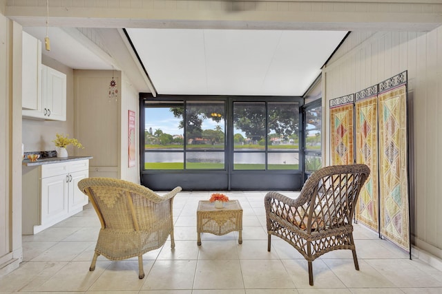 living area featuring lofted ceiling with beams, light tile patterned floors, and a water view