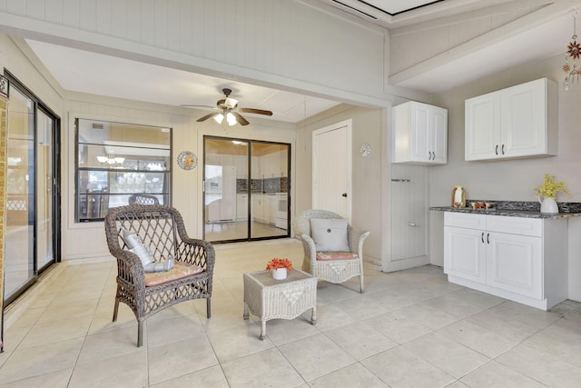 sitting room with ceiling fan, beamed ceiling, and light tile patterned flooring