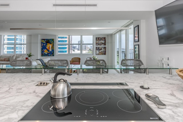 kitchen featuring light stone countertops, black cooktop, and visible vents