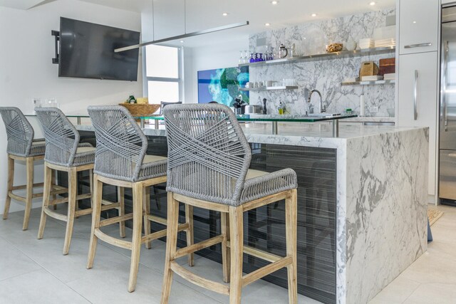 bar with light tile patterned floors, backsplash, and sink