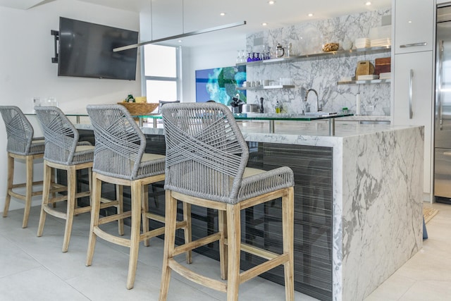 bar with a sink, stainless steel fridge, and indoor wet bar