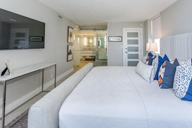 bedroom featuring a barn door, ensuite bath, and baseboards