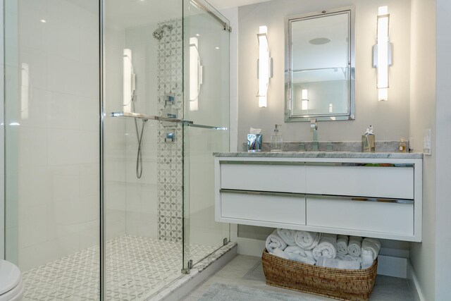 bathroom with tile patterned floors, a shower with door, vanity, and toilet