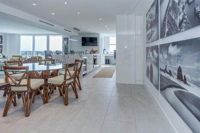 dining space with light tile patterned floors, beverage cooler, and expansive windows