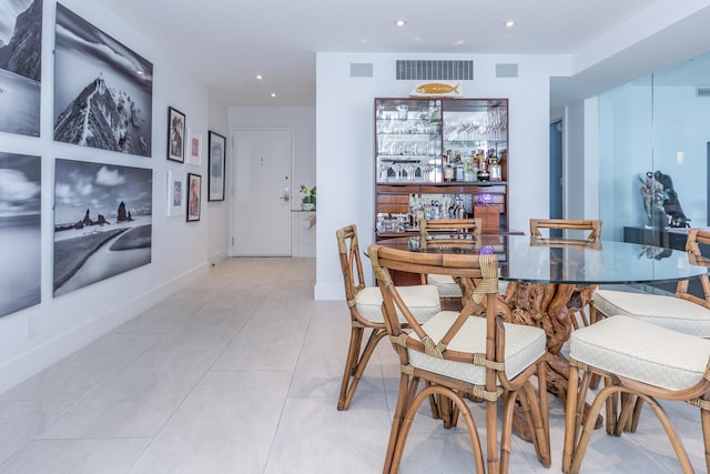 dining area featuring light tile patterned floors, recessed lighting, bar area, visible vents, and baseboards