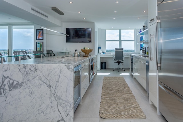 kitchen with recessed lighting, stainless steel appliances, built in study area, light stone countertops, and open shelves