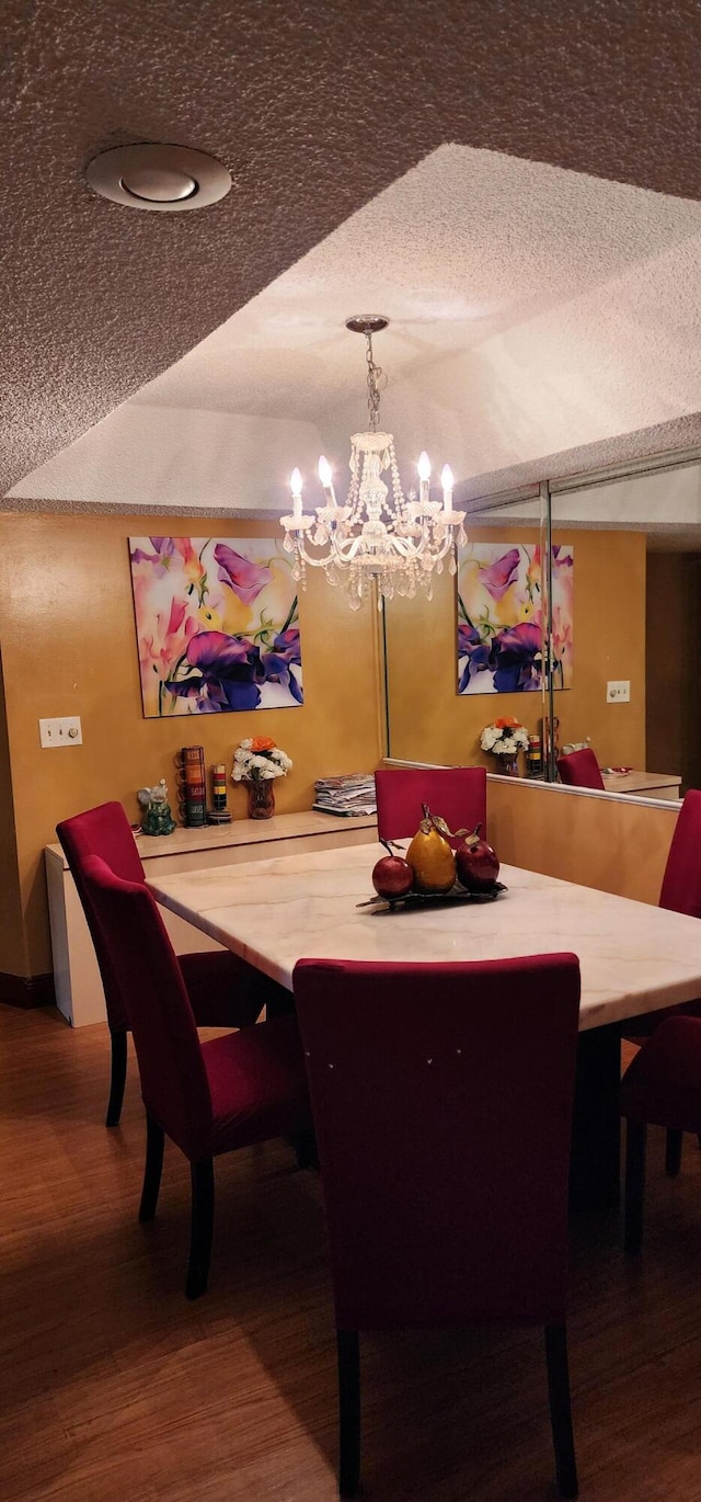 dining space with a textured ceiling, a notable chandelier, and hardwood / wood-style floors