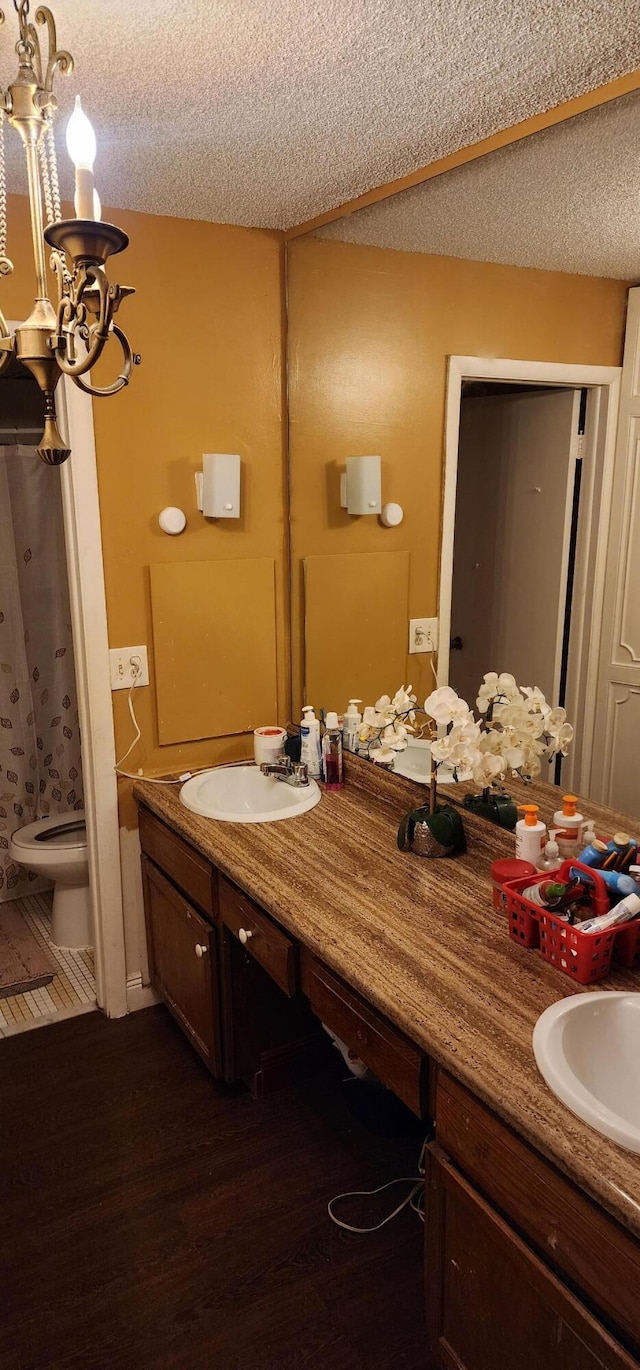 bathroom with wood-type flooring, a chandelier, a textured ceiling, vanity, and toilet